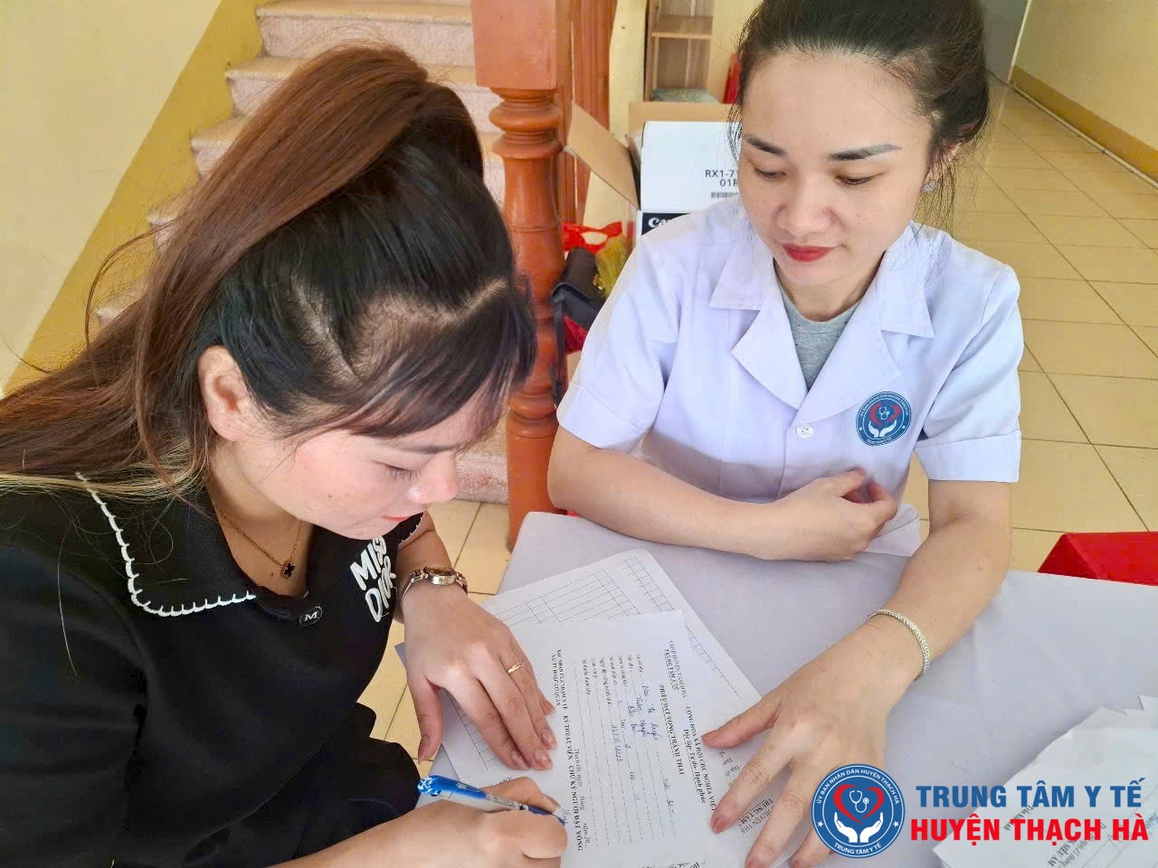 Nhân viên y tế hướng dẫn người dân hoàn thiện thông tin khám, tư vấn sức khỏe sinh sản trong Chiến dịch truyền thông lồng ghép KHHGĐ/CSSKSS năm 2025 tại Trạm Y tế xã.