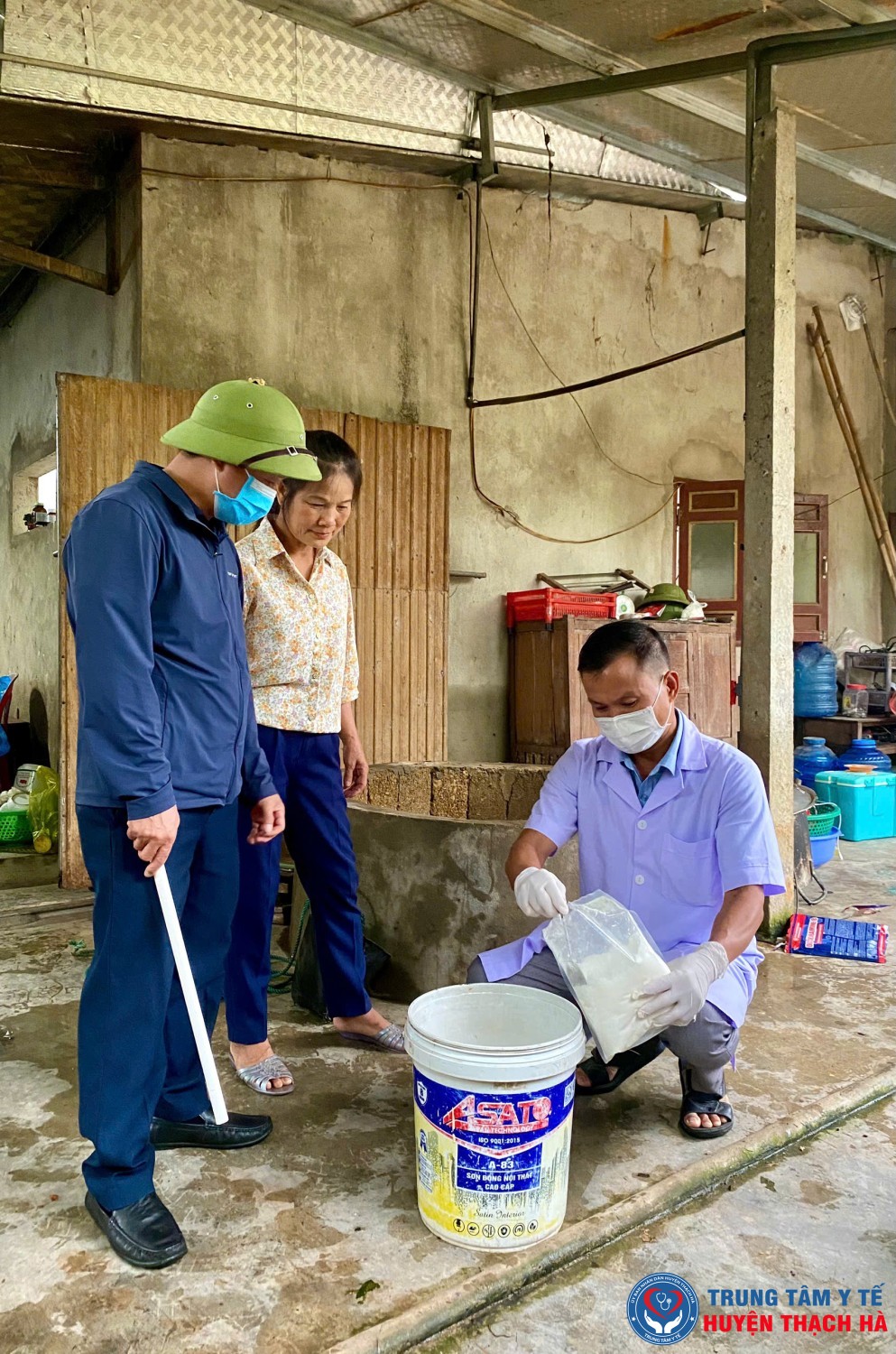 Cán bộ Trạm Y tế xã Thạch Ngọc đang hướng dẫn người dân xử lý nguồn nước sinh hoạt sau ngập lụt